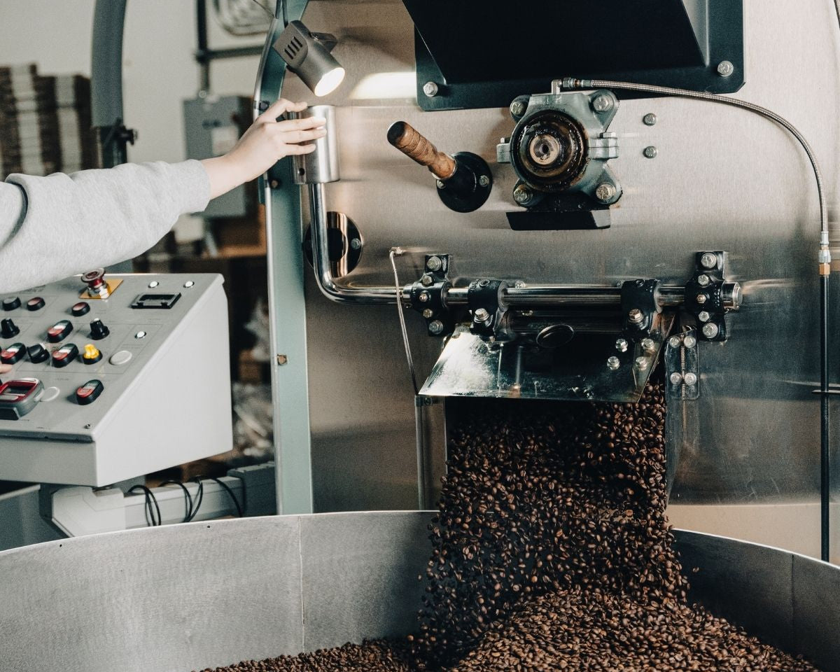 A worker controlling the roasting process for decaf coffee, illustrating the care taken with Ethyl Acetate (E.A.) beans.