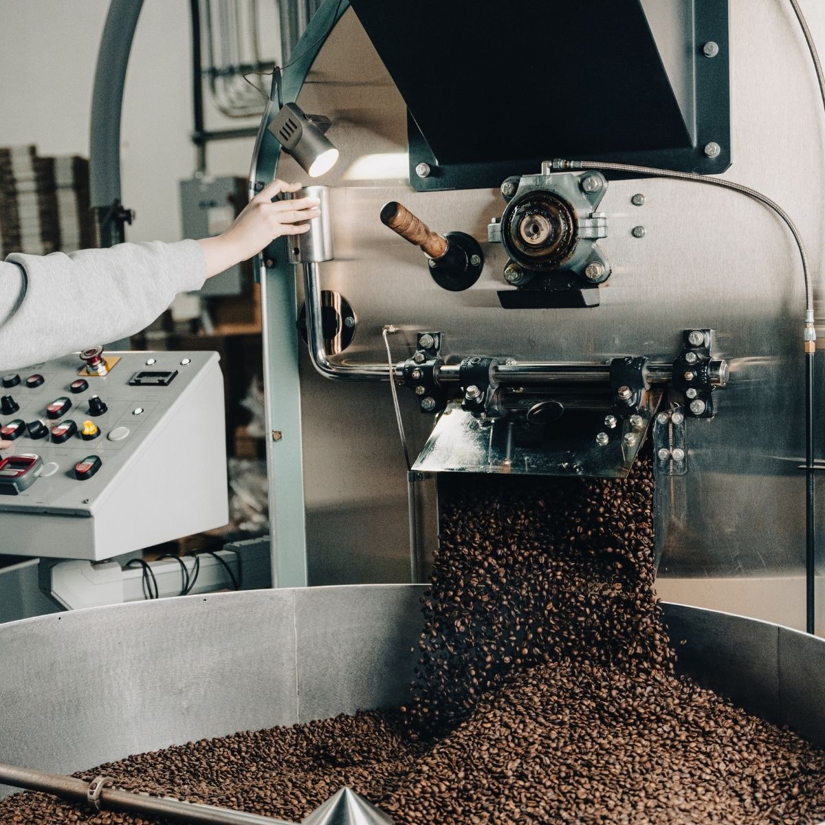A worker controlling the roasting process for decaf coffee, illustrating the care taken with Ethyl Acetate (E.A.) beans.